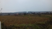 A mezőn túl Romhány városa, középen a csempegyár füstölög